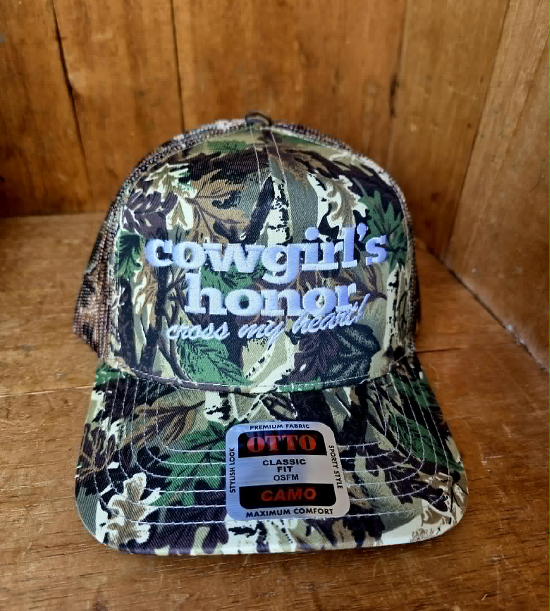 Western camouflage trucker cap featuring bold white embroidered lettering, curved brim, breathable mesh back, and vintage country styling for the ultimate cowgirl look 