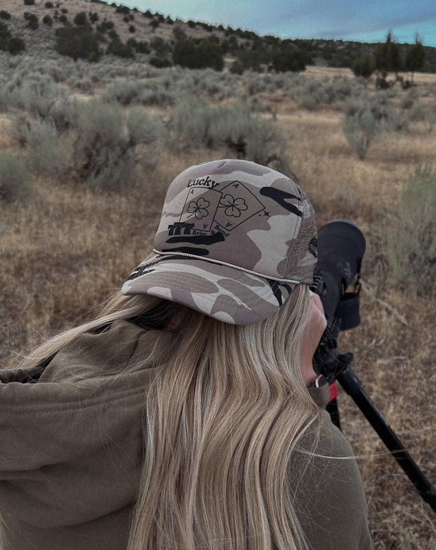 Neutral camo western camo cap with lucky playing cards graphic, with horseshoe detail and rope trim detail on five panel mesh back cap 