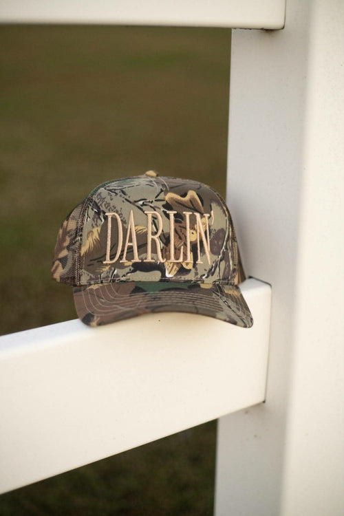 Camo full trucker cap with oversized gold "DARLIN" embroidery across the front