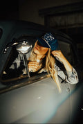Navy trucker cap with a curved brim, featuring white embroidered Western-style icons across the front panel, including horseshoes, stars, and playful symbols. The cap has a white rope detail along the base of the front panel and a mesh back, giving it a classic, casual Western-inspired look.