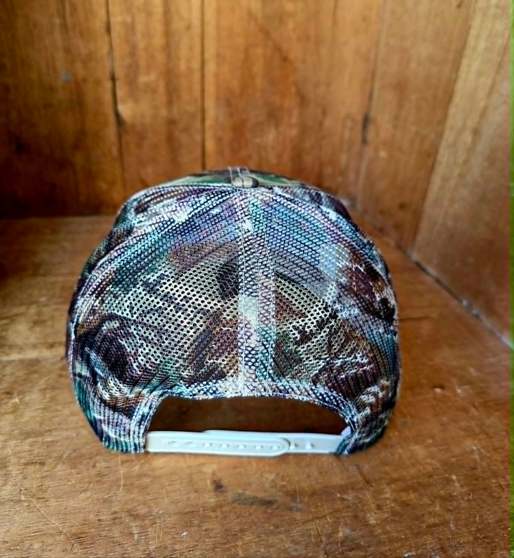 Rustic camo trucker hat with white statement embroidery, structured front panel, curved peak, and mesh backing. A bold western accessory for the cowgirls and country music lovers