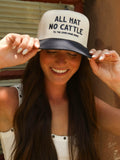 Women wearing a navy and cream western trucker cap embroidered with "All Hat No Cattle Till The Cows Come Home" while holding the brim outdoors in warm sunlight