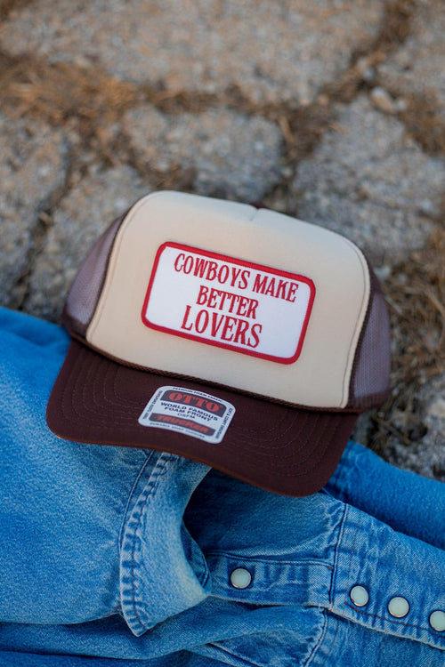 beige and brown western trucker cap with structured front panel featuring Cowboys Make Better Lovers. The cap has a brown curved brim, mesh back