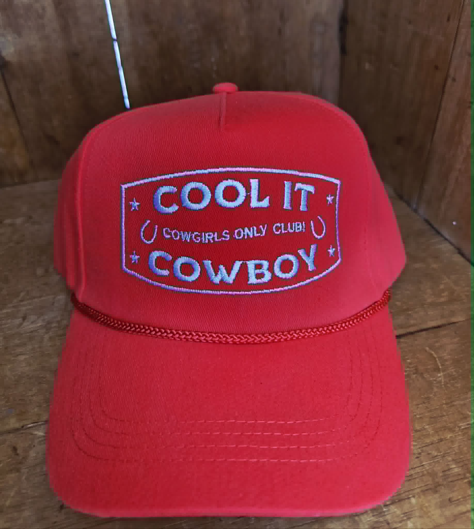 Red cowgirl inspired trucker cap with structured front panel, white embroidered western slogan, and classic rope detail across the brim, perfect for country music festivals and rodeo outfits