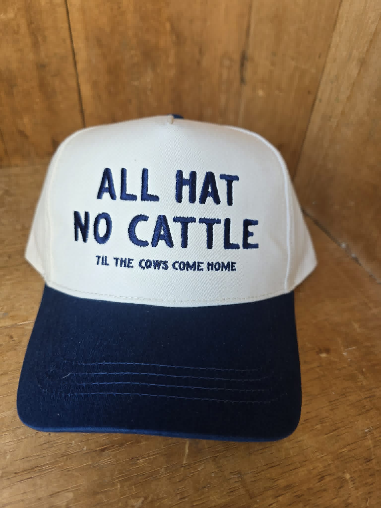 Dusty Cactus Co western trucker cap featuring navy embroidery on a cream front panel with classic country trucker hat fit and curved brim