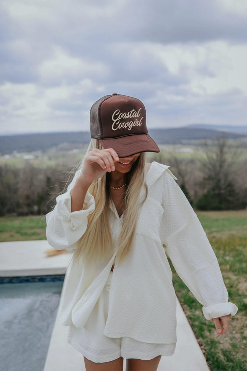Dusty Cactus Co chocolate brown trucker cap featuring cream "Coastal Cowgirl" embroidery ad classic mesh snapback design.