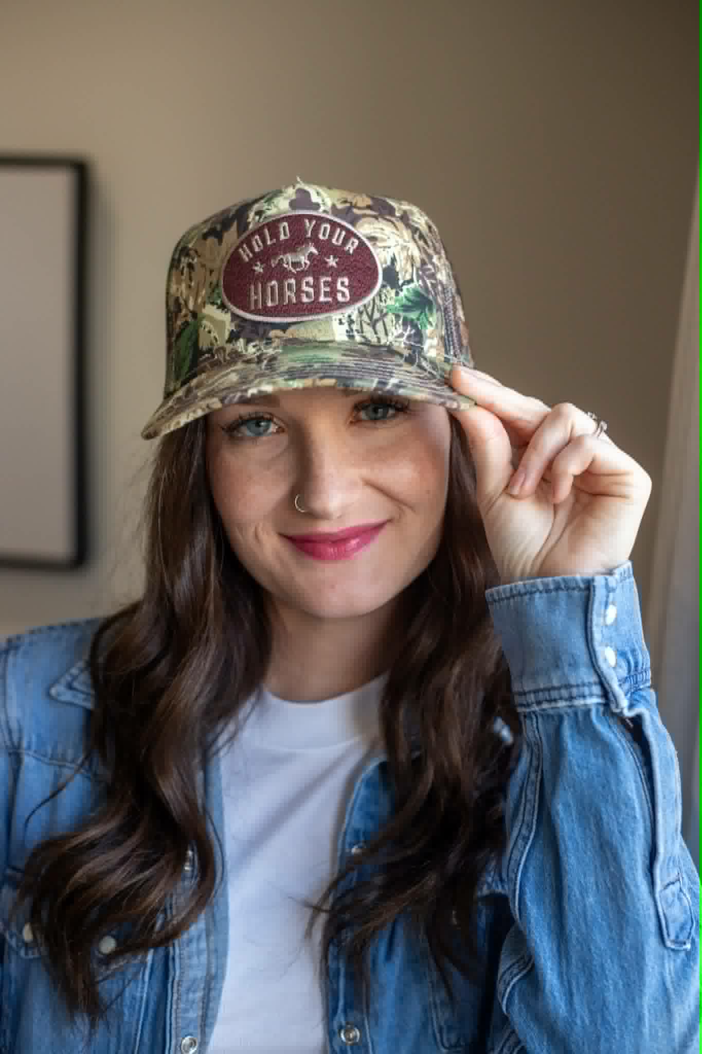 Camo trucker cap with a brown patch gold writing saying Hold Your Horses 